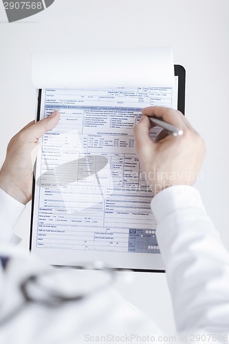 Image of male doctor holding prescription paper in hand