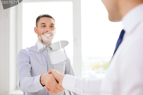 Image of two smiling businessmen shaking hands in office