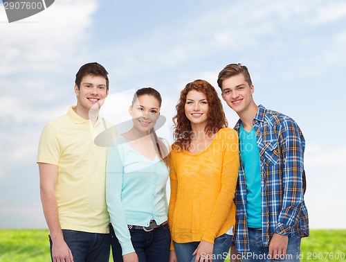 Image of group of smiling teenagers over blue sky and grass