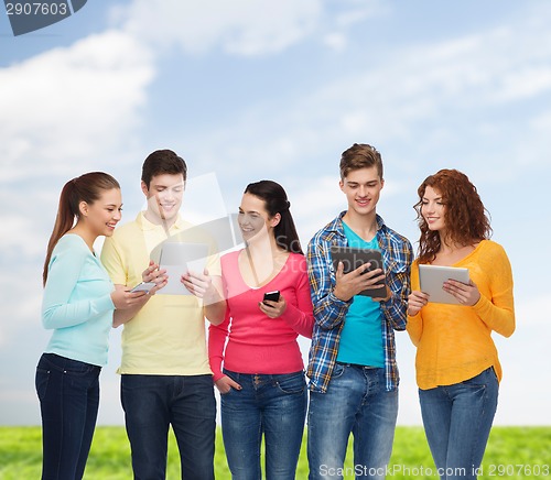 Image of group of teenagers with smartphones and tablet pc