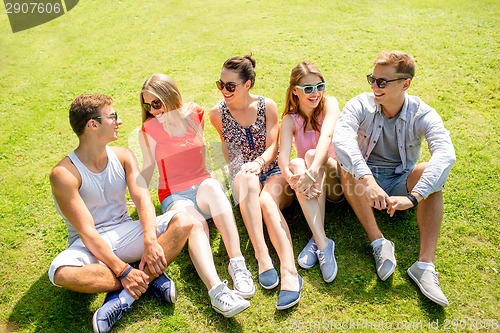 Image of group of smiling friends outdoors sitting in park