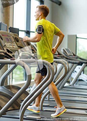 Image of man with smartphone exercising on treadmill in gym