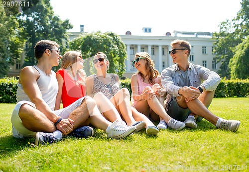 Image of group of smiling friends outdoors sitting in park