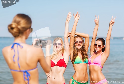 Image of group of smiling women photographing on beach