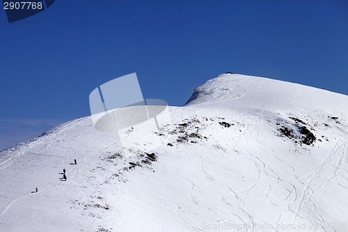 Image of Snowboarders and skiers downhill on off piste slope at sun day