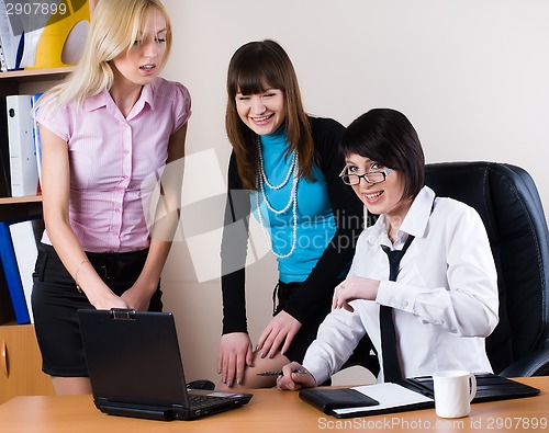 Image of Three pretty businesswomen communicate in office