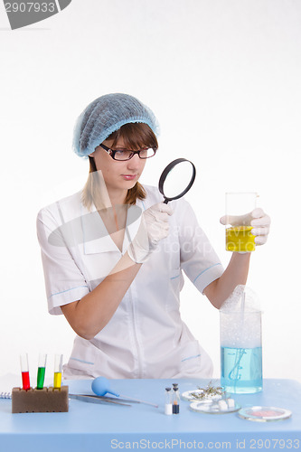 Image of Chemist looking at the liquid in flask