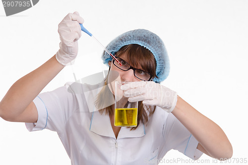 Image of Chemist finds drops falling into a flask