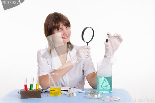 Image of Pharmacist considers powder through a magnifying glass