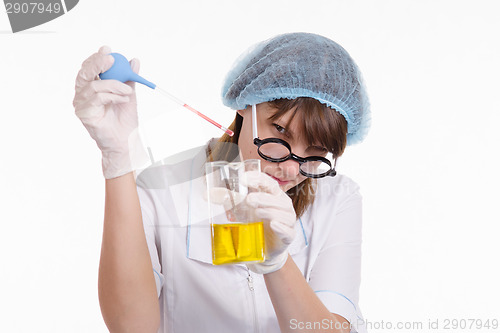 Image of Laboratory assistant liquid drips from a pipette into flask