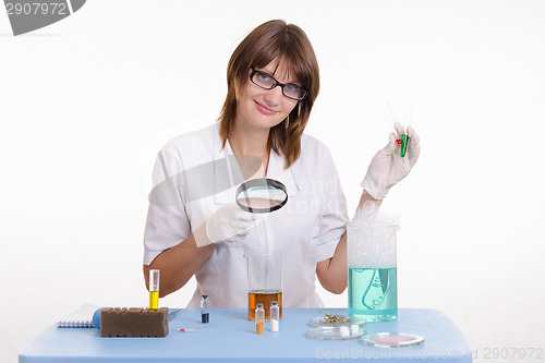 Image of Chemist examines the contents of flask