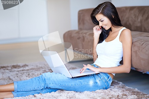 Image of Woman smiling as she surfs the net on a laptop