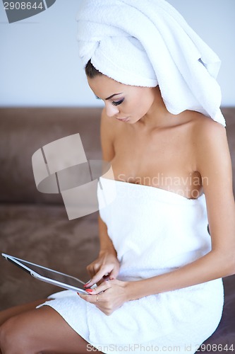 Image of Woman Wearing Bath Towel and Using Tablet Computer