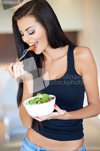 Image of Tanned healthy young woman enjoying a mixed salad