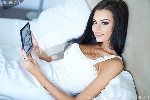 Image of Smiling beautiful woman relaxing in bed