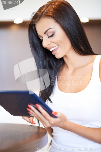 Image of Happy young woman surfing on a tablet-pc