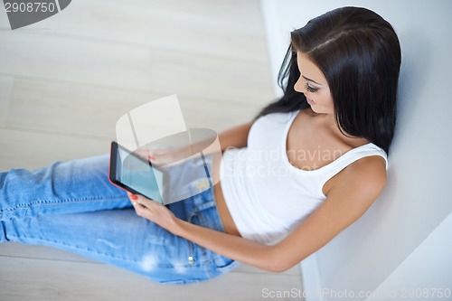 Image of Casual young woman relaxing with a tablet