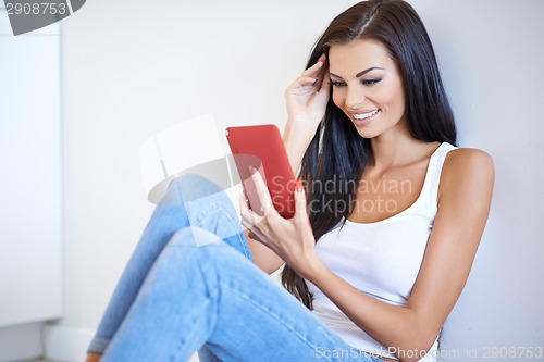 Image of Smiling woman reading information on her tablet