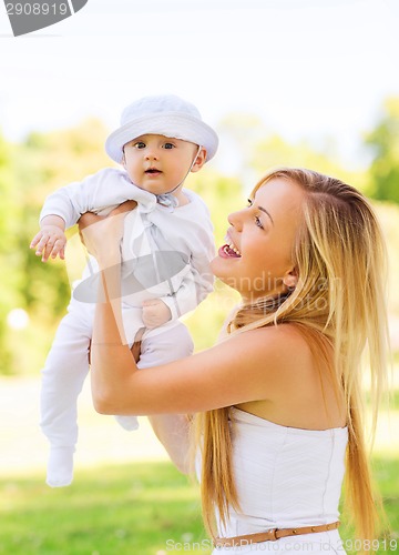 Image of happy mother with little baby sitting on blanket