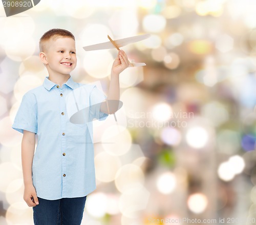 Image of smiling little boy holding a wooden airplane model