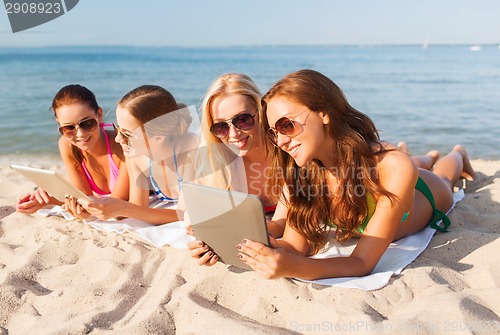 Image of group of smiling young women with tablets on beach