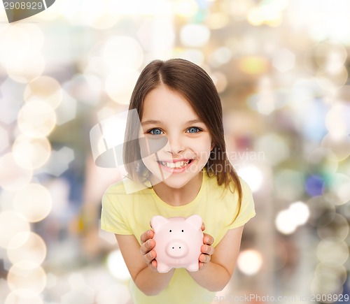 Image of beautiful little girl with piggy bank