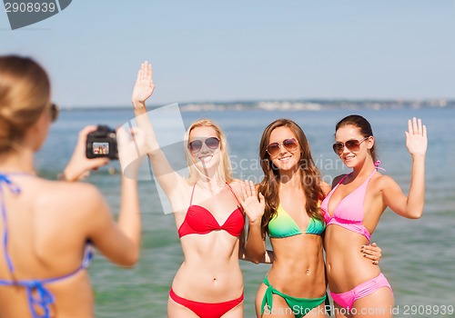 Image of group of smiling women photographing on beach