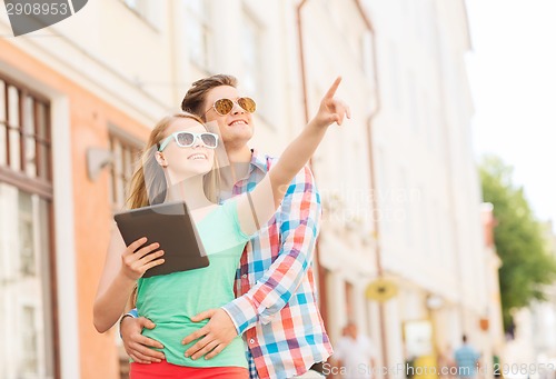 Image of smiling couple with tablet pc in city