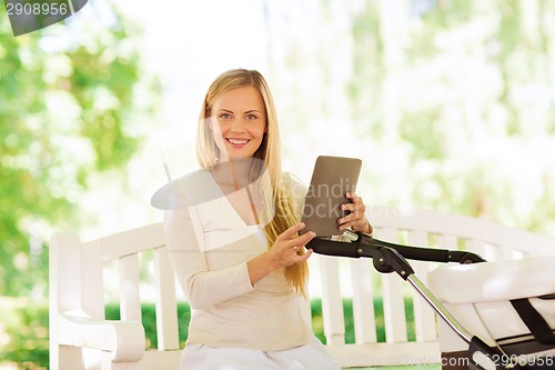 Image of happy mother with tablet pc and stroller in park