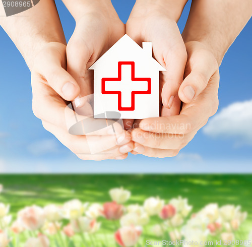 Image of hands holding paper house with red cross