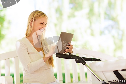 Image of happy mother with tablet pc and stroller in park