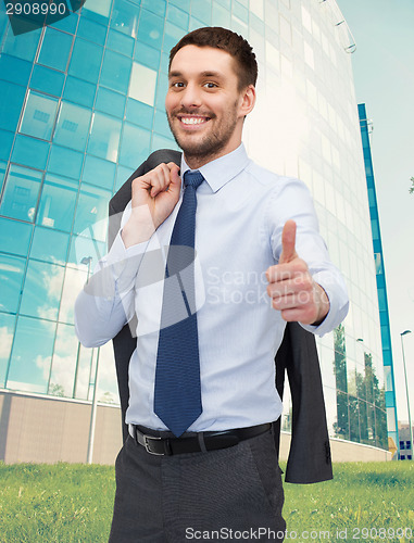 Image of smiling young businessman showing thumbs up