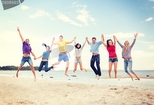 Image of group of friends jumping on the beach