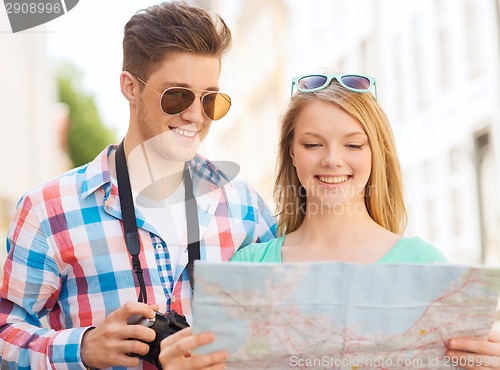 Image of smiling couple with map and photo camera in city