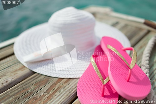 Image of close up of hat, sunscreen and slippers at seaside