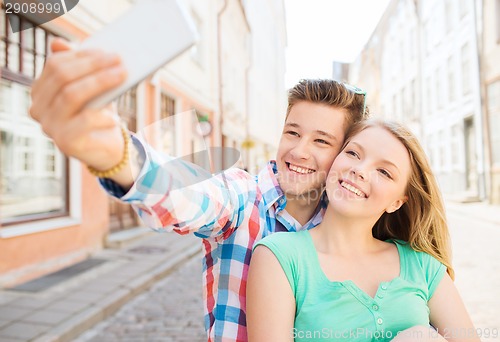 Image of smiling couple with smartphone in city