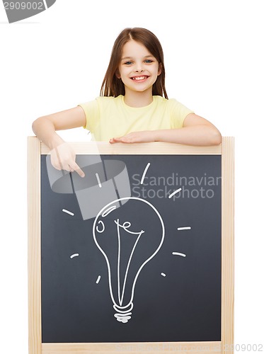 Image of smiling little girl pointing finger to blackboard