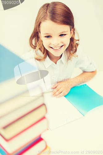 Image of smiling little student girl with many books