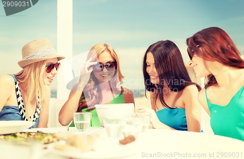 Image of smiling girls looking at tablet pc in cafe