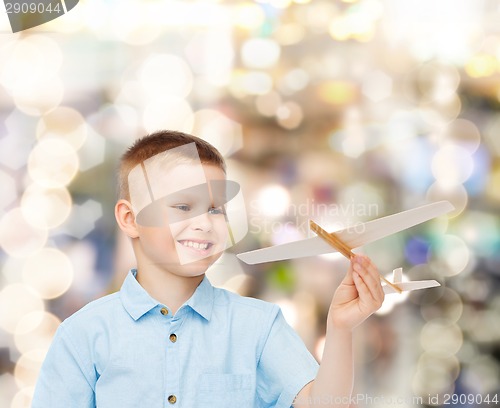 Image of smiling little boy holding a wooden airplane model