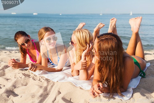Image of group of smiling women in sunglasses on beach