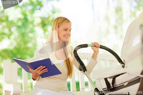 Image of happy mother with book and stroller in park