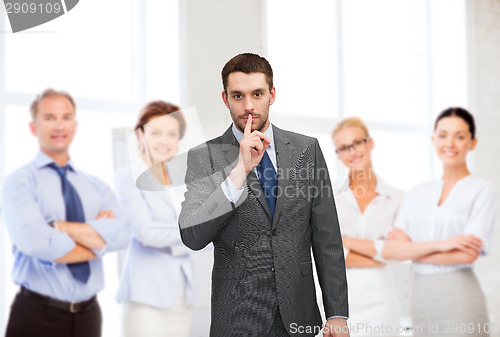 Image of group of smiling businessmen making hush sign