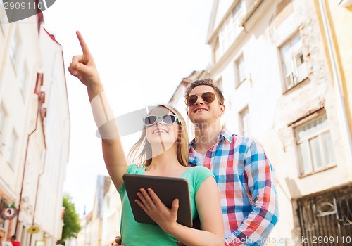 Image of smiling couple with tablet pc in city