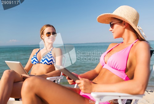 Image of smiling women with tablets pc computers on beach