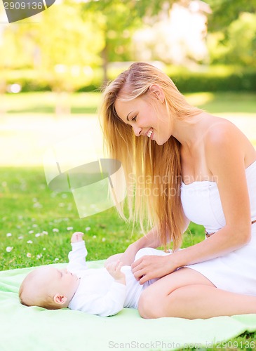 Image of happy mother lying with little baby on blanket