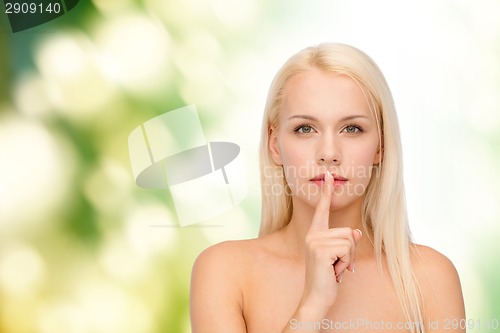 Image of calm young woman with finger on lips