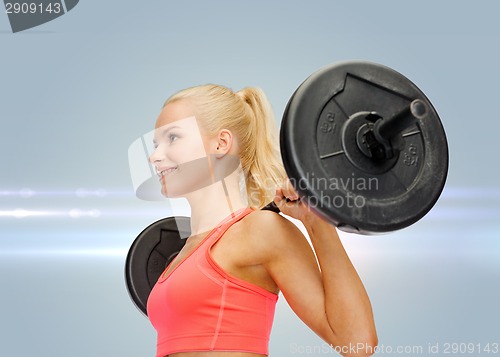 Image of smiling sporty woman exercising with barbell