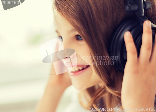 Image of smiling little girl with headphones at home