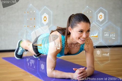 Image of smiling woman doing exercises on mat in gym